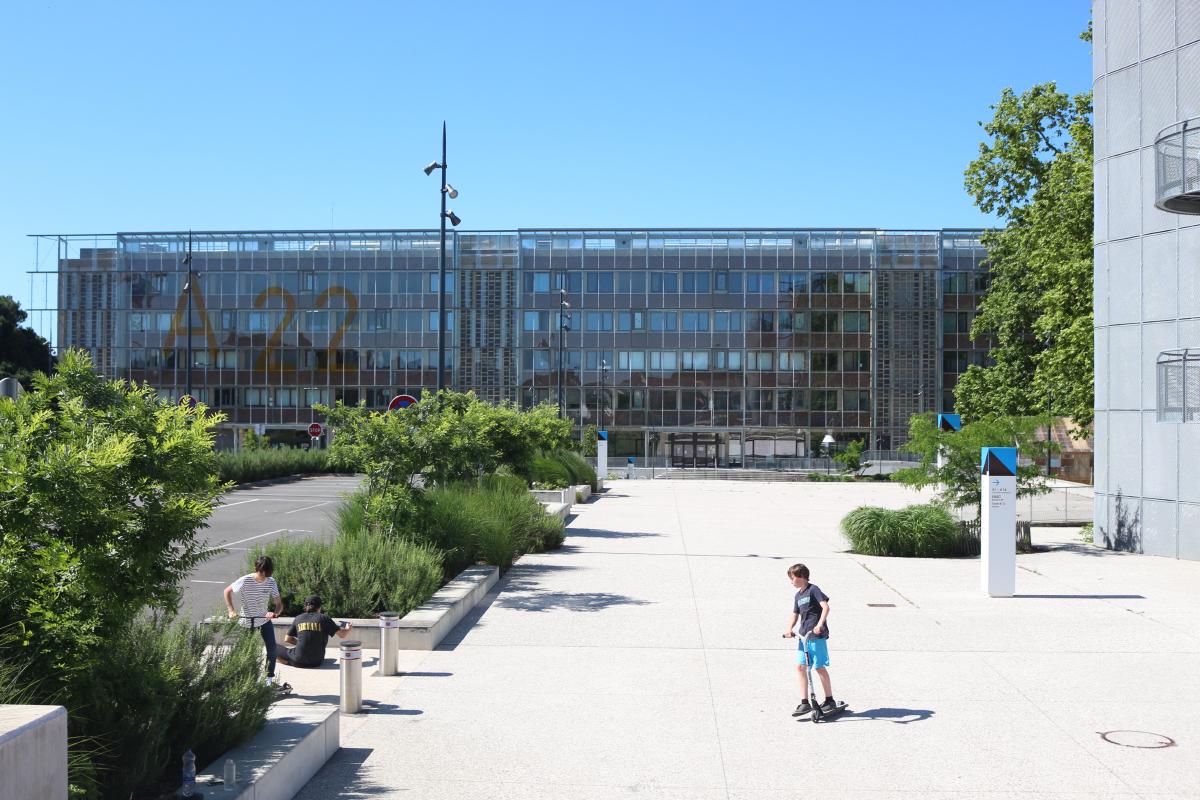 L'esplanade du bâtiment A22 de l'Université de Bordeaux, avec au premier plan trois jeunes en trottinette mécanique.